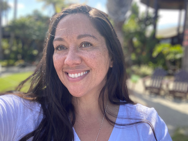 Photo of Zeenia Junkeer smiling, standing outside on a sunny day.